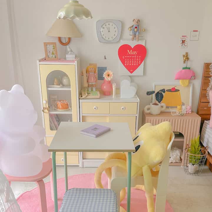柔らかい黄色とピンクの色調の小さなダイニングスペース、子供のおもちゃやポスターが配置された雰囲気のある部屋