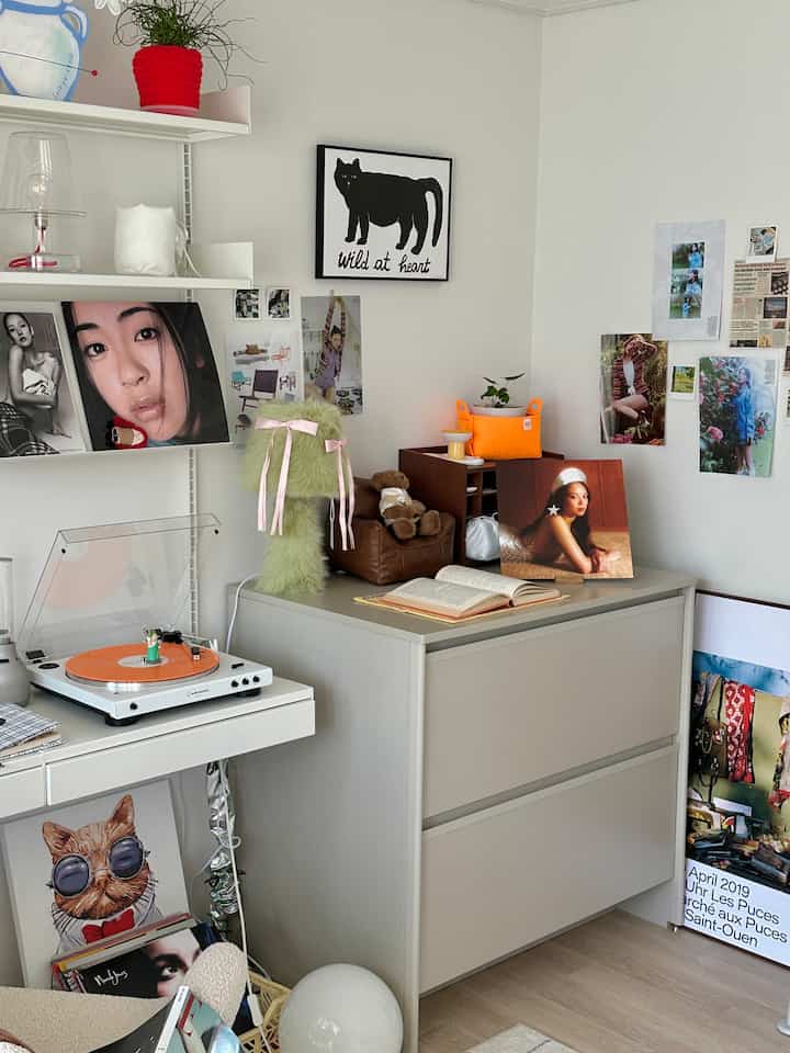 White and gray toned study featuring an orange vinyl turntable, various posters, and picture frames creating a stylish ambiance