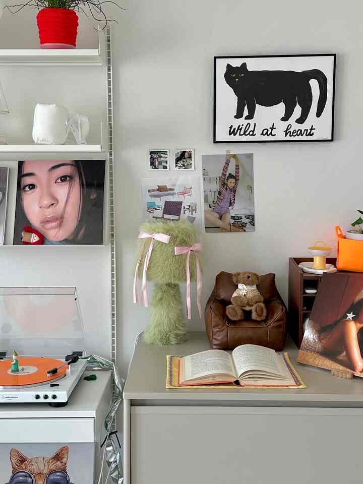 A white walled room with brown furniture, featuring a turntable and black cat poster, styled with cozy natural modern decor
