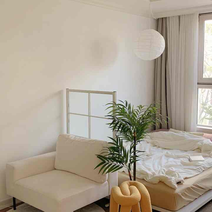 白とベージュの色調のワンルーム、ソファとベッド、パーティションが配置されたナチュラルでミッドセンチュリーモダンな雰囲気のインテリア