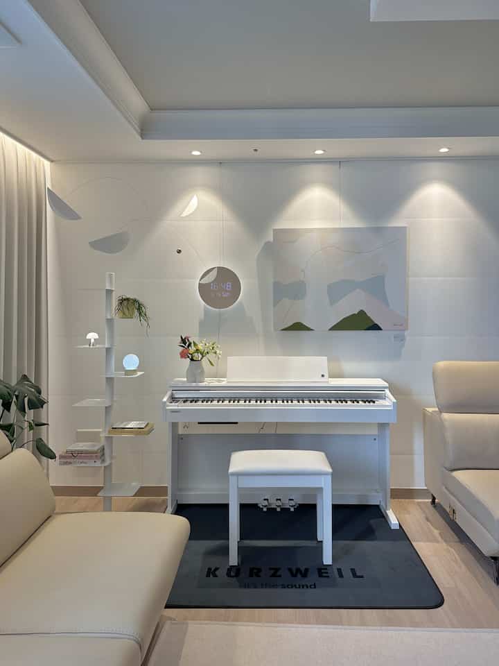 White and beige toned living room featuring a digital piano and sofas with a clean, modern atmosphere