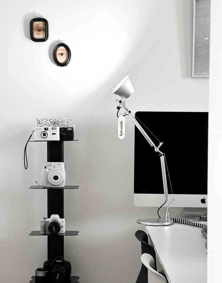 A compact home office space with white walls and black shelving, featuring a minimal and modern interior design