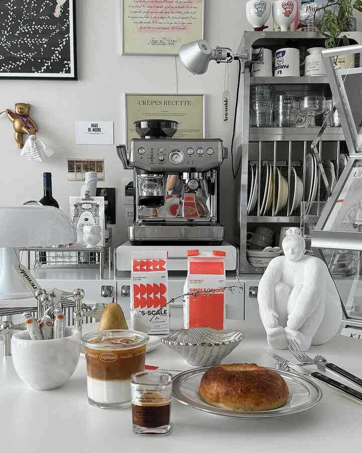 ホワイトとシルバーの色調のホームカフェ、ブレビルのエスプレッソマシンとテーブルウェアが配置された洗練されたモダンなインテリア