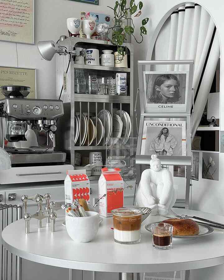 Modern kitchen-cafe space in white and gray tones, featuring coffee and bread on table with clean, minimalist design