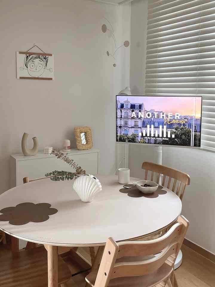 Bright white and natural brown toned dining room featuring round dining table and wooden dining chairs in a minimal setting