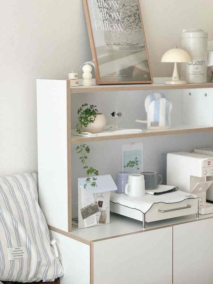 White-toned shelf unit in a home cafe space, featuring a coffee machine and various neat objets with a cozy ambiance