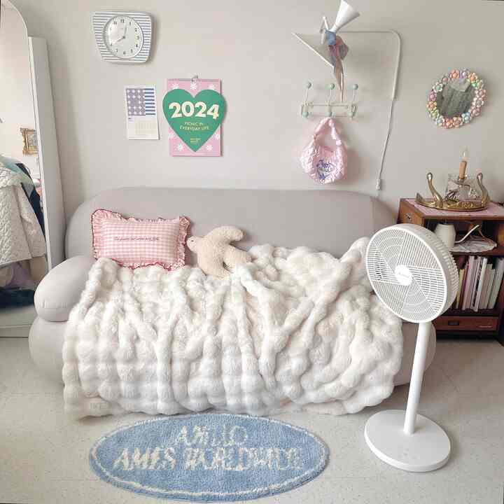 ホワイトとベージュの色調のリビング、ソファにふわふわのスローがかかり、ヴィンテージの収納キャビネットが温かみのある雰囲気を作り出すインテリア