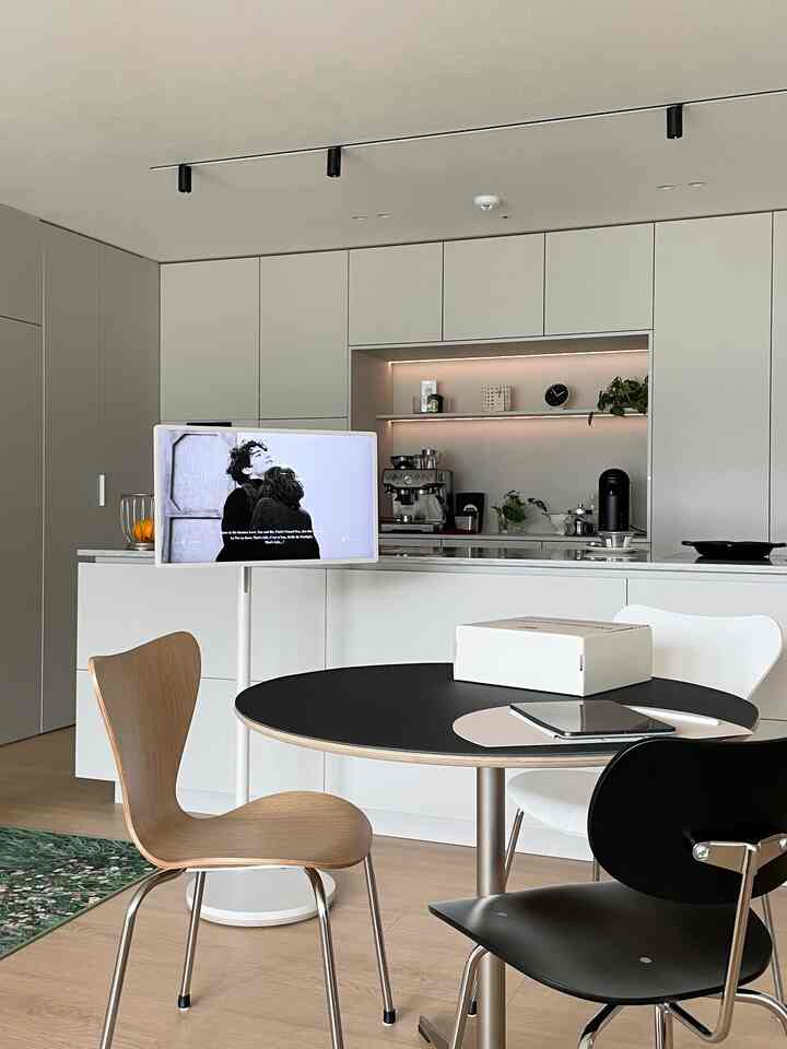 ホワイトとブラックの調和が取れたモダンなキッチンとダイニングルーム、木製チェアと黒の丸テーブルが配された印象的な空間