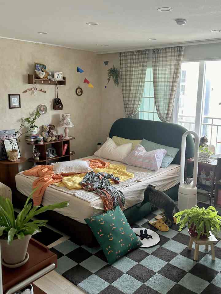 ヴィンテージな木目調の寝室、チェックカーテンとラグ、クッション、猫のいる雰囲気あるインテリア