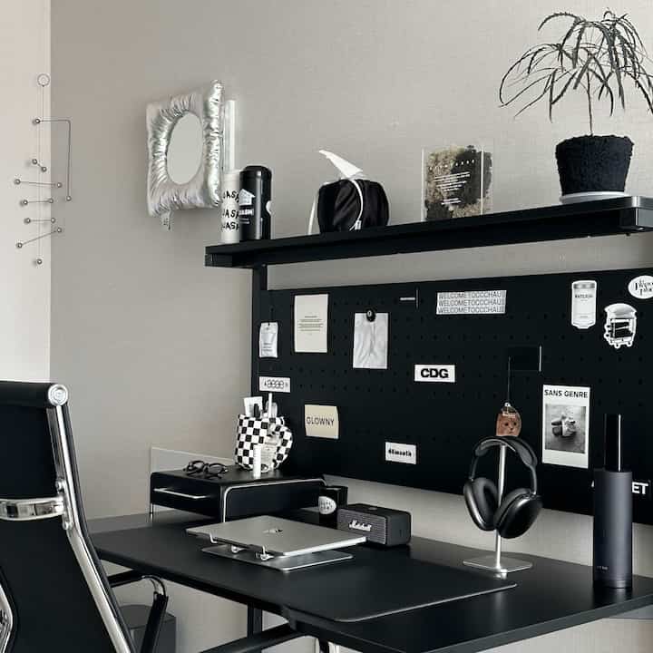 ブラックトーンのホームオフィス、ミッドセンチュリーモダンスタイルのデスクと収納ボックス、棚の上に植物が置かれた印象的な空間