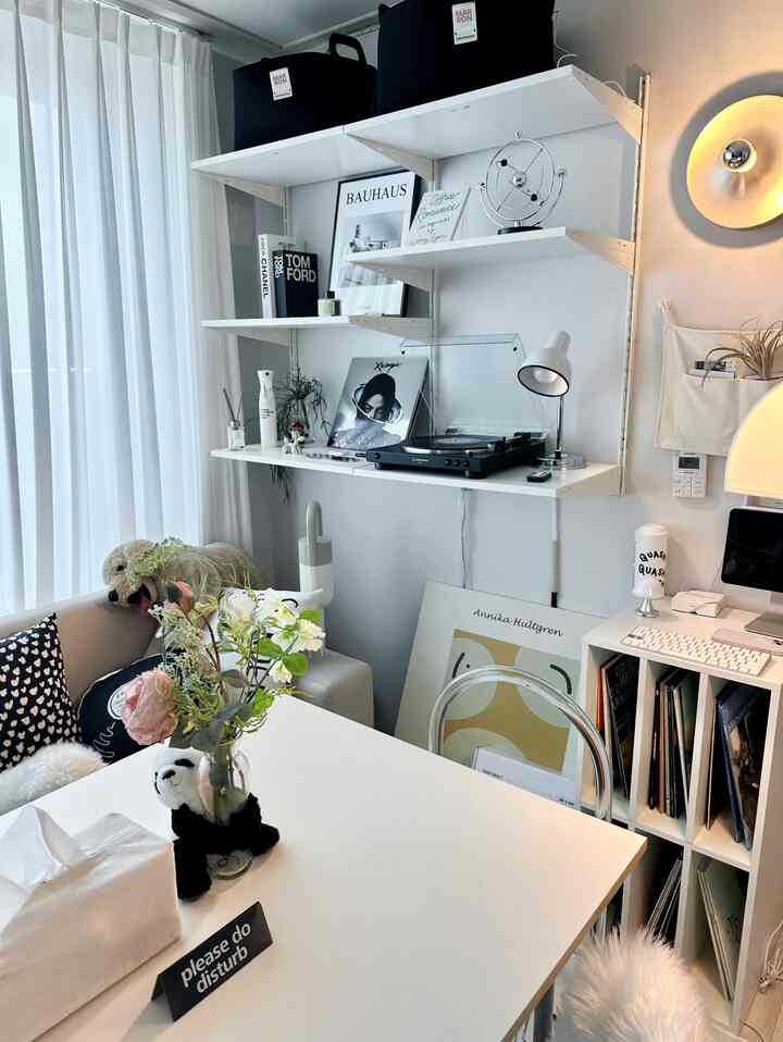 白を基調としたミッドセンチュリーモダンのホームオフィス、ヴィンテージのターンテーブルとレタリングクッションが配置された雰囲気のあるインテリア