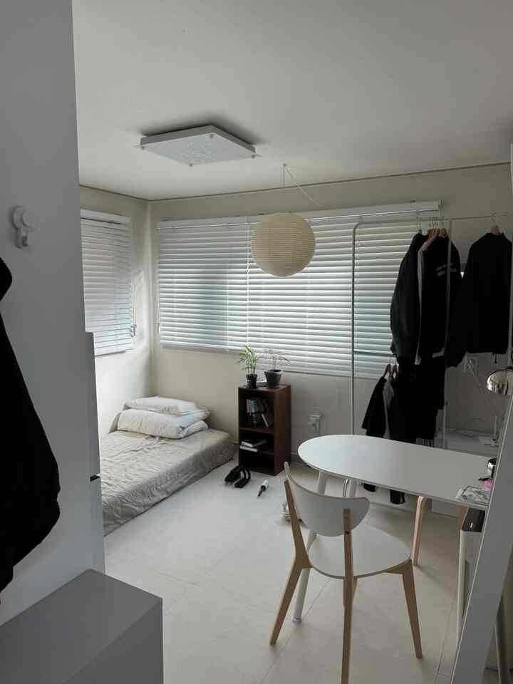 明るいホワイトトーンのワンルーム、ミニマルスタイルでシンプルなダイニングテーブルと椅子が配置された居心地の良い一人暮らし空間