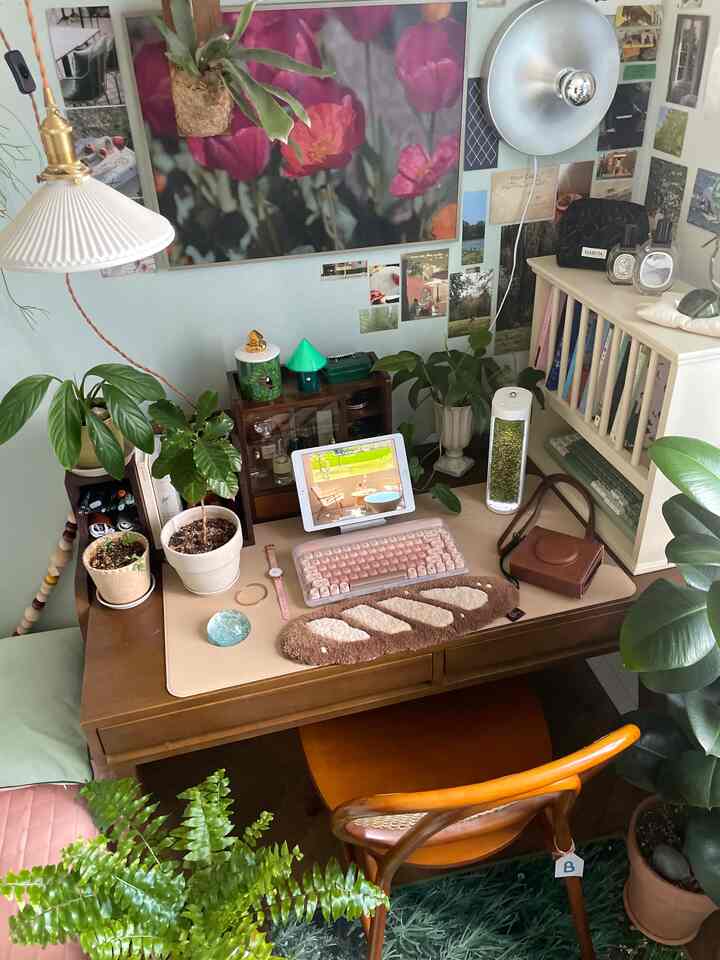 ナチュラルな木目調と緑の植物が調和した、温かみのあるホームオフィス。机とかわいらしい小物が配置された印象的な空間