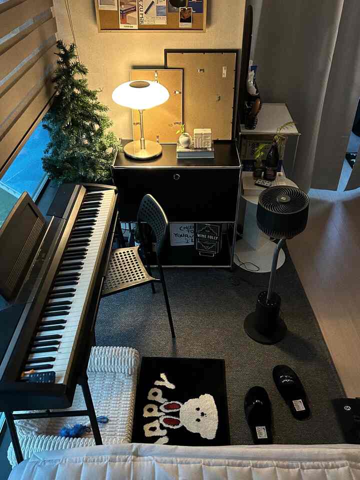 ライトグレーとブラックのトーンによるワンルームのリビング、電子ピアノとテーブルランプ、カーペットで空間を仕切ったモダンな雰囲気のインテリア