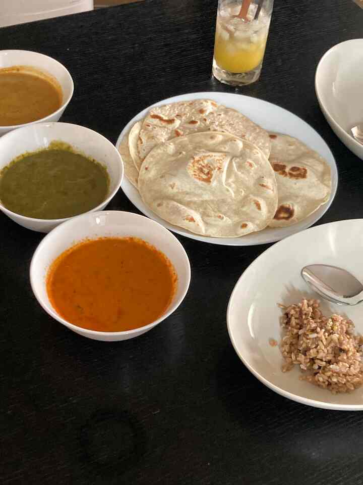 暗いトーンのキッチンテーブルにカレー三種、ナン、米が配置されたシンプルな食卓の雰囲気