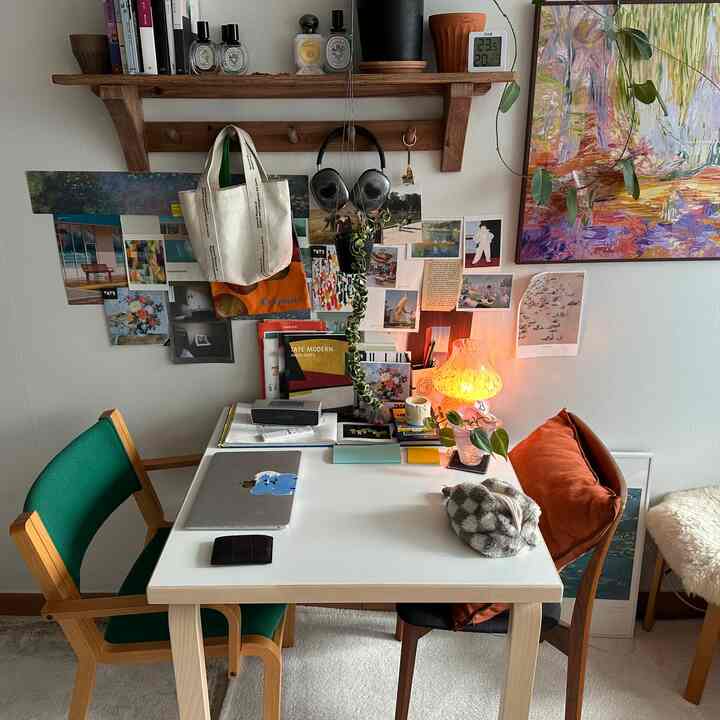 ホワイトのデスクとウッドトーンの椅子があるワンルームのホームオフィス、ヴィンテージ感のある明るく居心地の良い作業空間