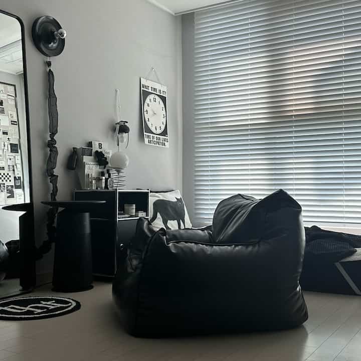 黒を基調としたワンルームリビング、ビーズクッションソファとブラインドが配置されたシンプルモダンなインテリア