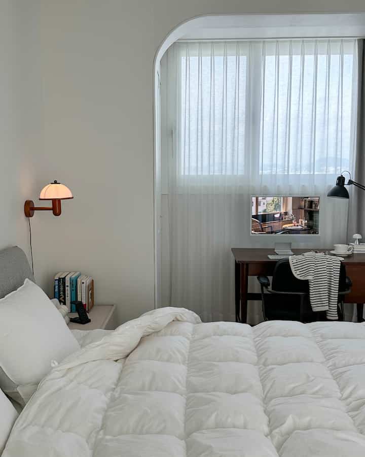 White and brown toned bedroom featuring a desk with office chair by the window creating a cozy home office setup