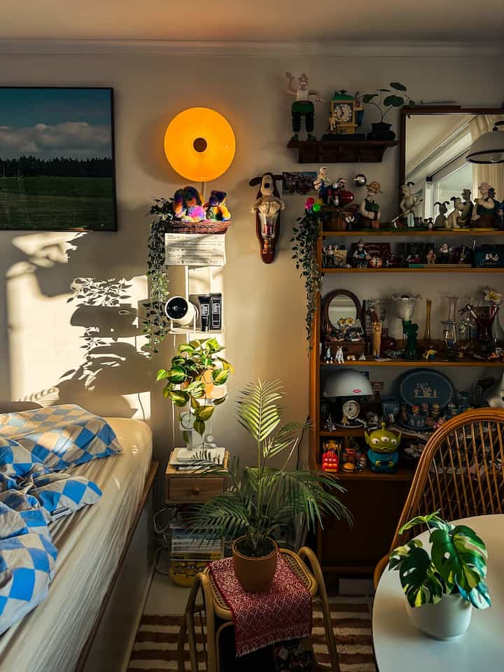 温かみのある木目調とヴィンテージ照明が調和した、装飾品や造花が並ぶ雰囲気のある寝室