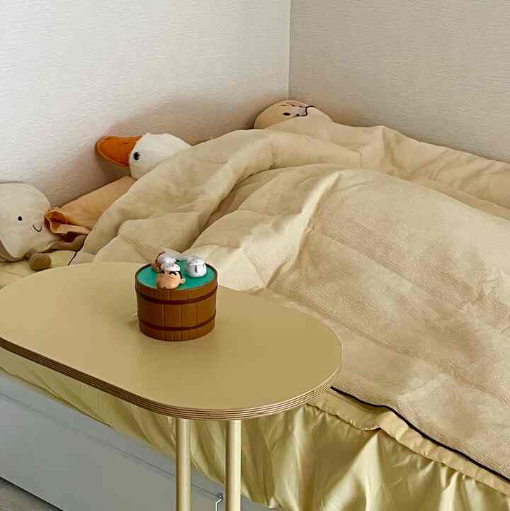 黄色とアイボリーの色調の寝室で、ミニマルなナイトテーブルと心地よい寝具が配置された雰囲気のあるインテリア