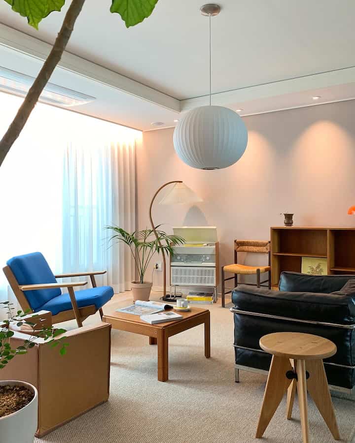 Natural color Nordic living room featuring mid-century modern furniture with blue armchair in a warm and cozy atmosphere