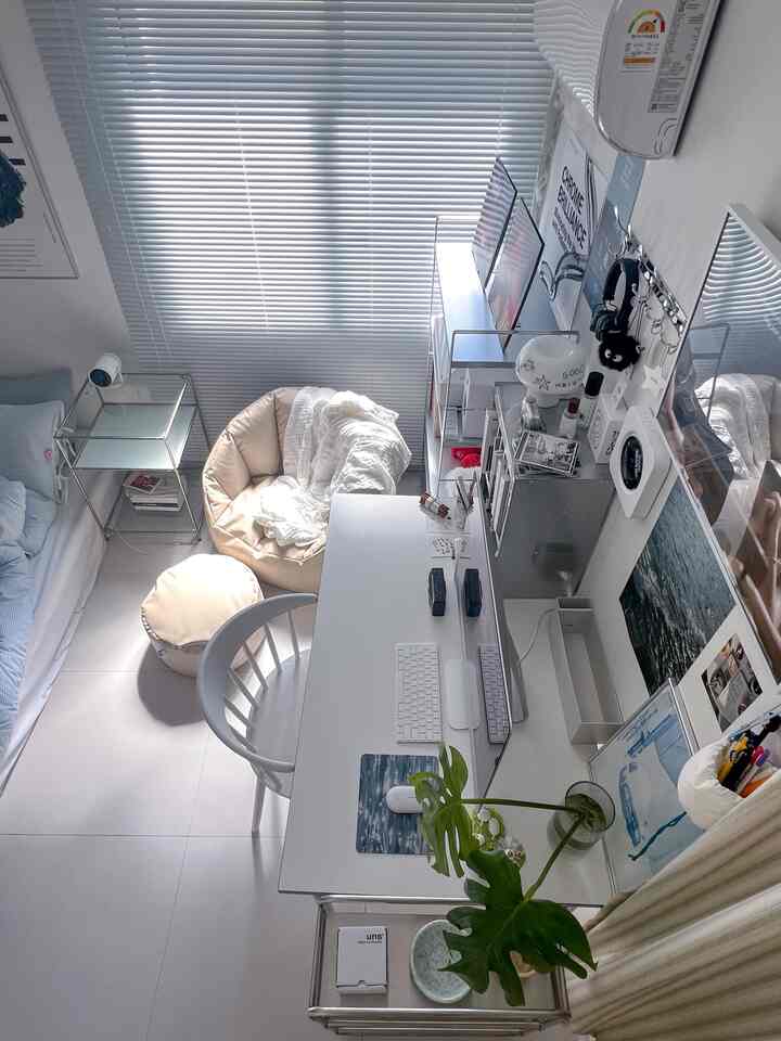 白を基調としたコンパクトなワンルーム、デスクとベージュのビーンバッグチェアが配置された雰囲気のあるホームオフィス