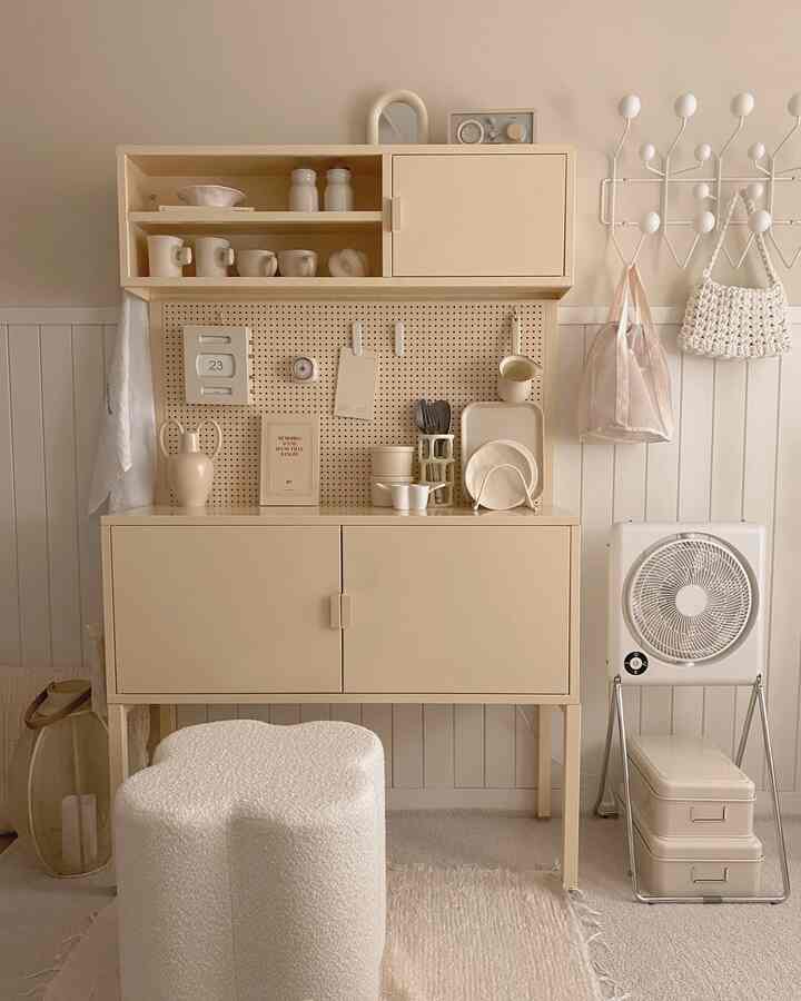 柔らかなバター色とベージュ調のホームカフェ空間、中央にバター色のキャビネットと手前に花形の白いスツールが配置された温かみのあるインテリア