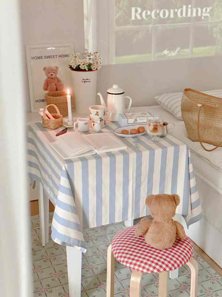 Natural-toned small dining area featuring a table with striped tablecloth, teddy bear, vase of flowers creating a cozy ambiance