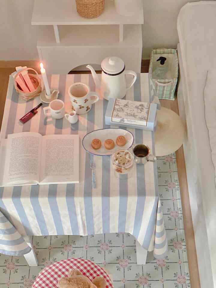 ホワイトとベージュのトーンが調和したリビング、ストライプのテーブルクロスとコーヒーセットが配置された温かみのあるおうちカフェ空間