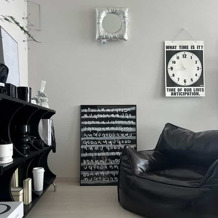 モノトーンとナチュラルカラーの調和したワンルームリビング、黒のビーンバッグソファと額縁が配置された印象的な空間