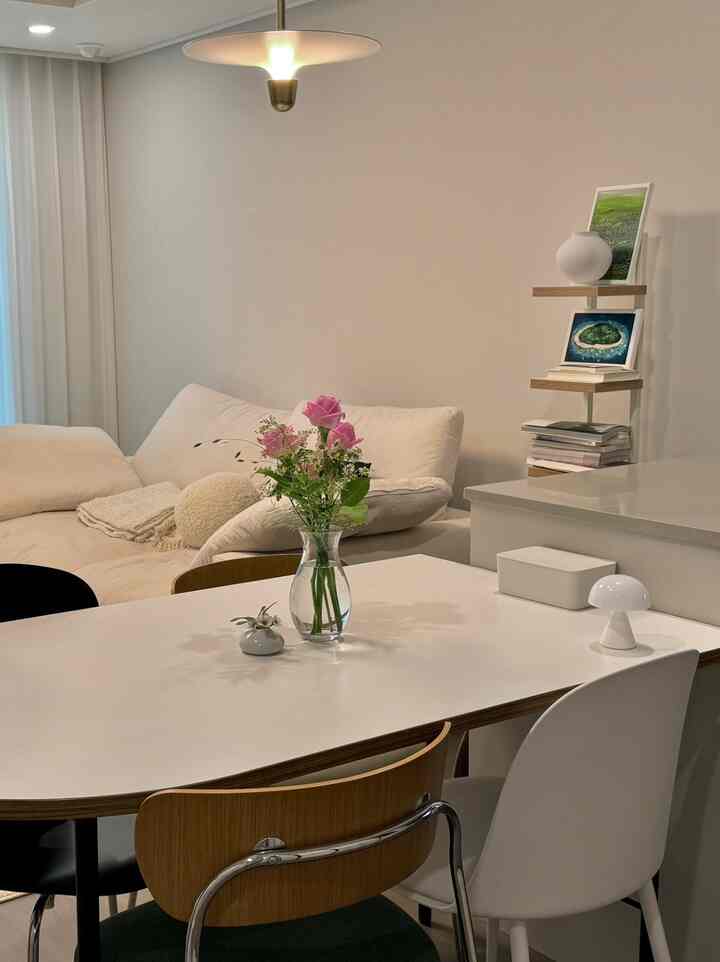 ナチュラルカラーのリビング、白いソファとダイニングチェアが配置された清潔感のある雰囲気の空間