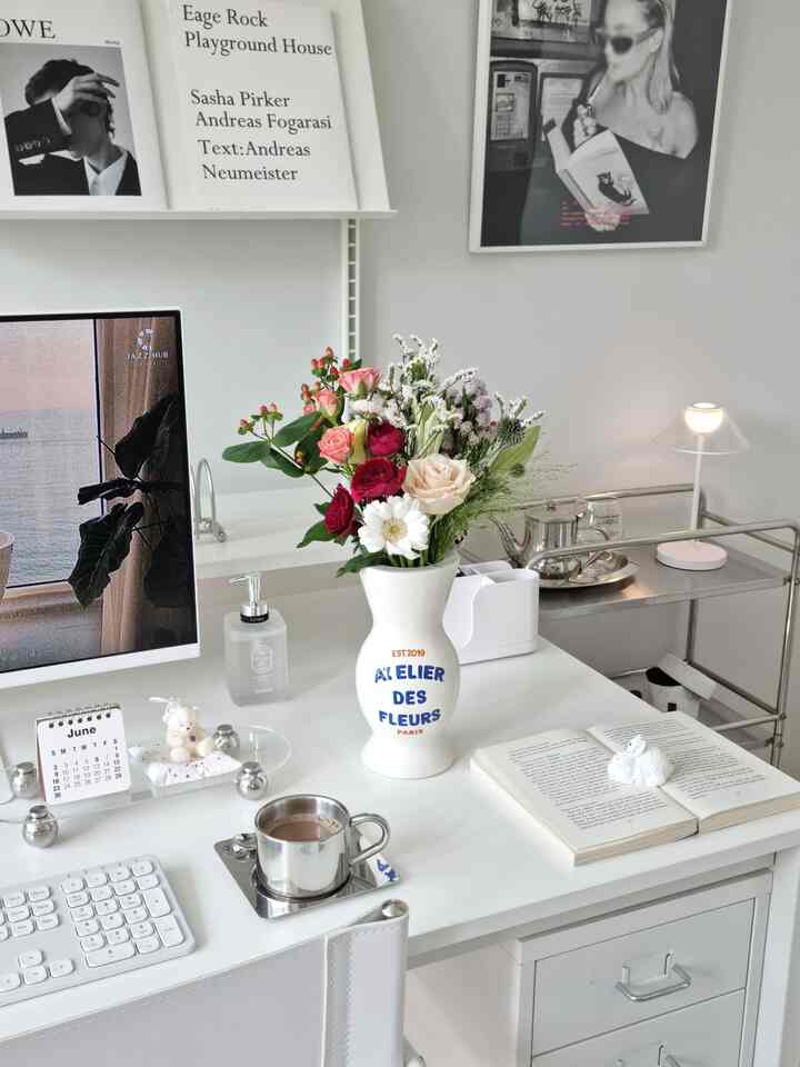 白を基調とした書斎、花瓶や照明、本、コーヒーカップが置かれた印象的なモダンなホームオフィス