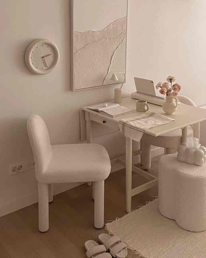 アイボリーとベージュの色調のホームオフィス、机と椅子、壁の時計と花瓶が配置されたシンプルで自然な雰囲気のあるインテリア