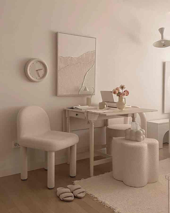 ナチュラルな色調のホームオフィス、クリーム色のデスクと椅子、スツール、ラグが配置された雰囲気のあるインテリア