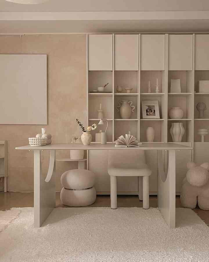 ベージュとホワイトの色調のリビング書斎、白い机と椅子、本棚、ナチュラルなオブジェが配置された雰囲気のあるインテリア