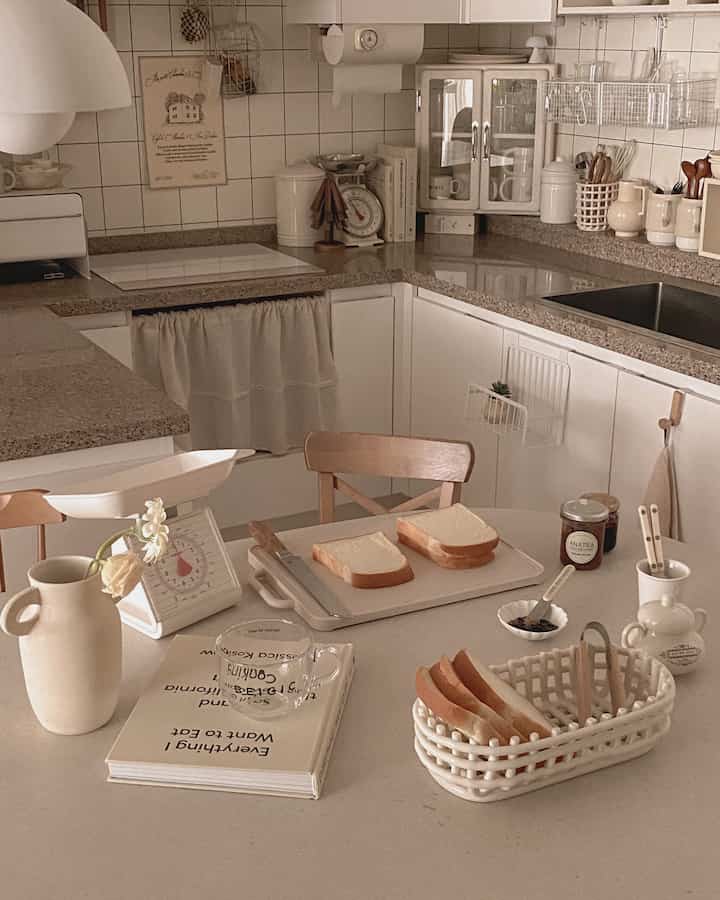 温かみのあるホワイトとブラウン調のキッチン、ヴィンテージの秤とかわいらしい小物が配置された雰囲気のあるインテリア