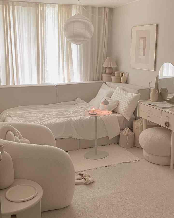 柔らかなクリーム色の寝室、ソファベッドと丸いサイドテーブル、自然な照明とすっきりとしたモダンなインテリアが調和した空間