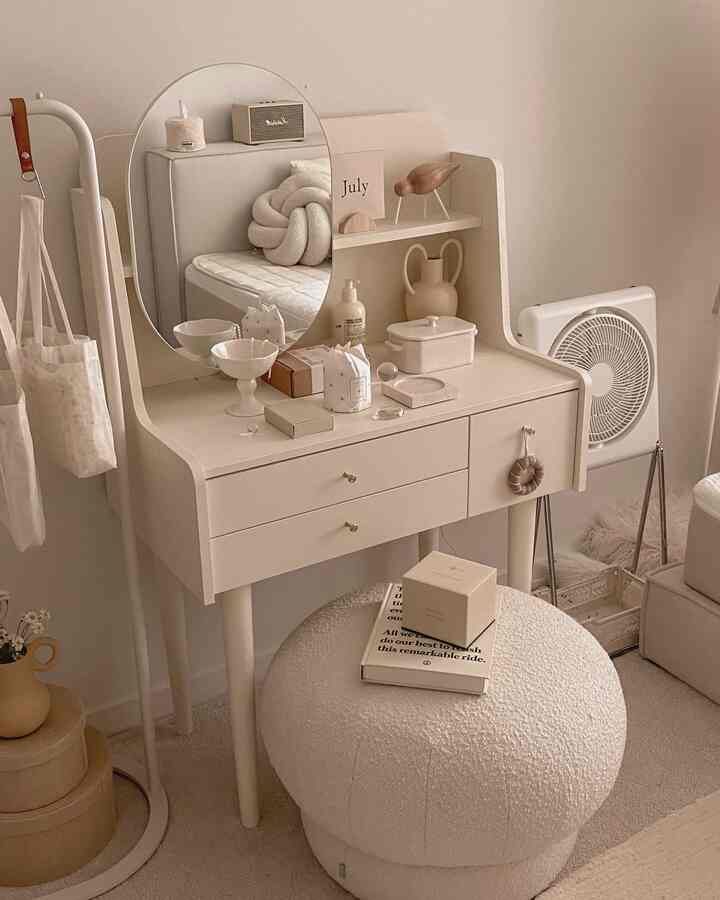 ベージュ調のコンパクトな化粧台空間、丸い鏡とクリーム色のスツールが配置された雰囲気のあるナチュラルモダンなインテリア