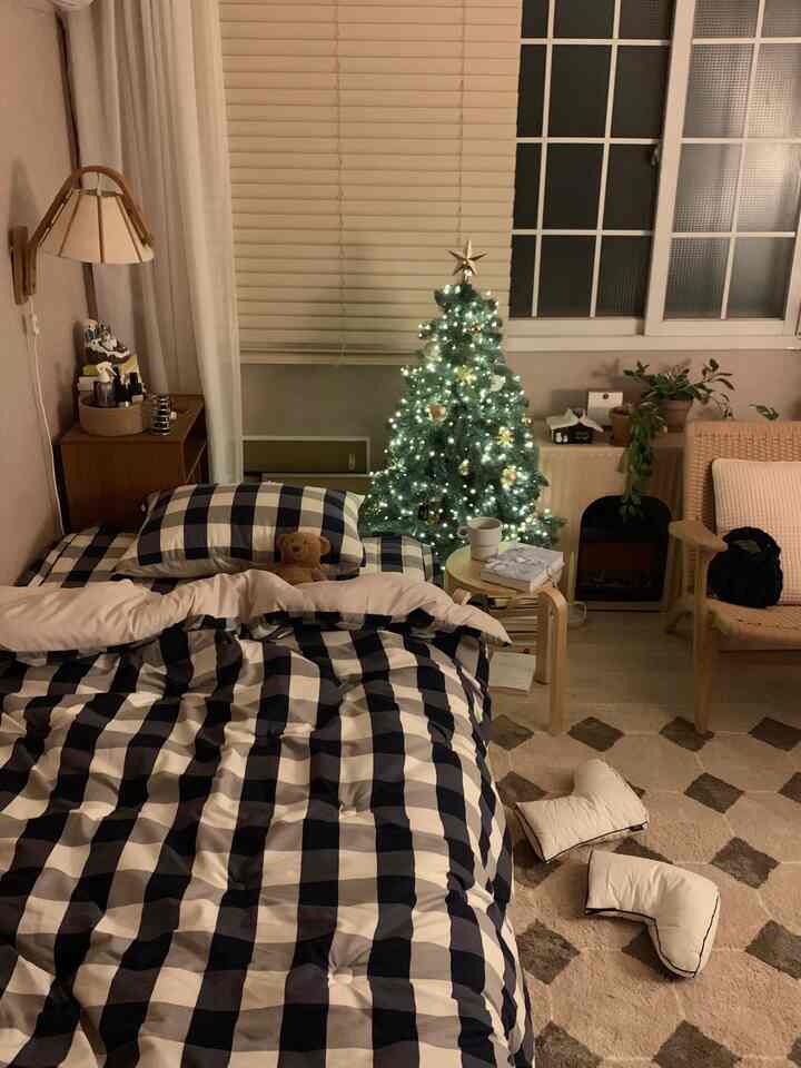 ネイビーとホワイトのチェック柄ベッドリネンが配置された寝室、クリスマスツリーとナチュラルな木製家具が調和した雰囲気のあるインテリア