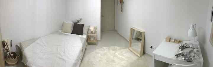 Ivory and wood tone bedroom featuring bed, nightstand, full-length mirror, and desk creating a cozy atmosphere