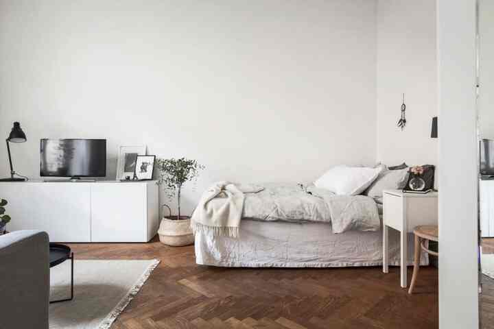 Bright white and wood-tone studio apartment of 8 pyeong, featuring bed and sofa in a natural modern setting