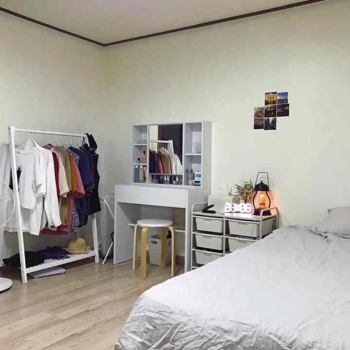 White tone bedroom featuring clothing rack, vanity desk, and storage drawers with a clean and simple atmosphere