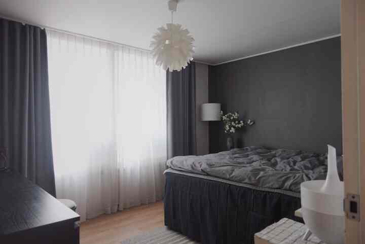 A white and gray toned bedroom featuring a bed and curtains with a simple, modern ambiance