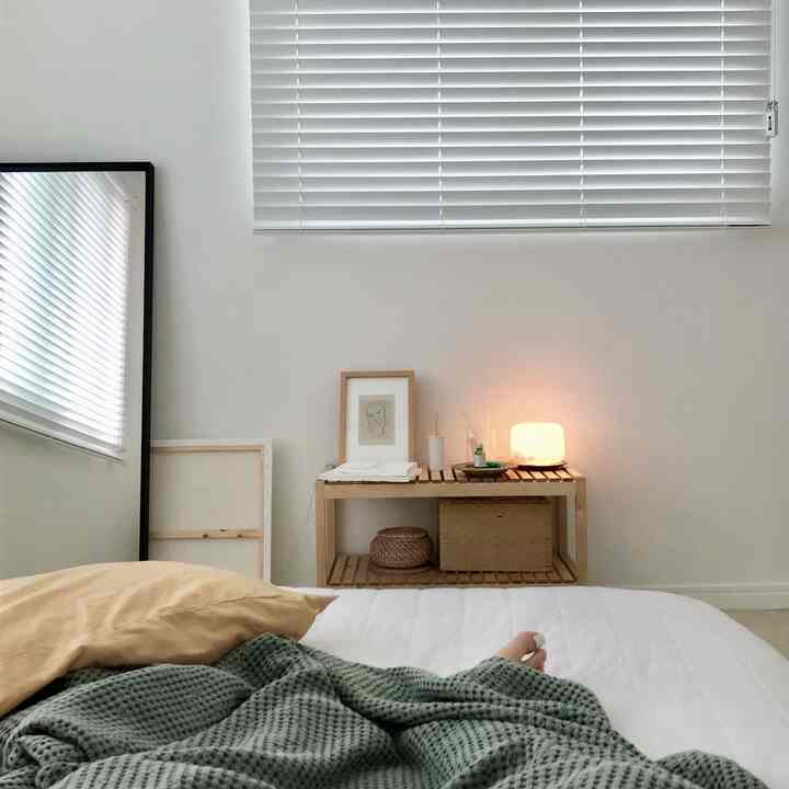 White and wood tone bedroom featuring bed and soft lamp with a simple natural atmosphere