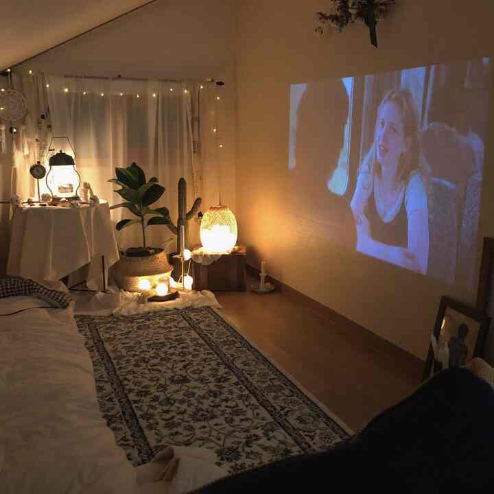 Natural tone loft with warm lighting and projector, candles and plants arranged creating a cozy atmosphere