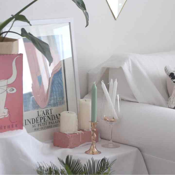 White-toned living space featuring a white sofa, candles, and a picture frame in a simple and elegant Nordic interior