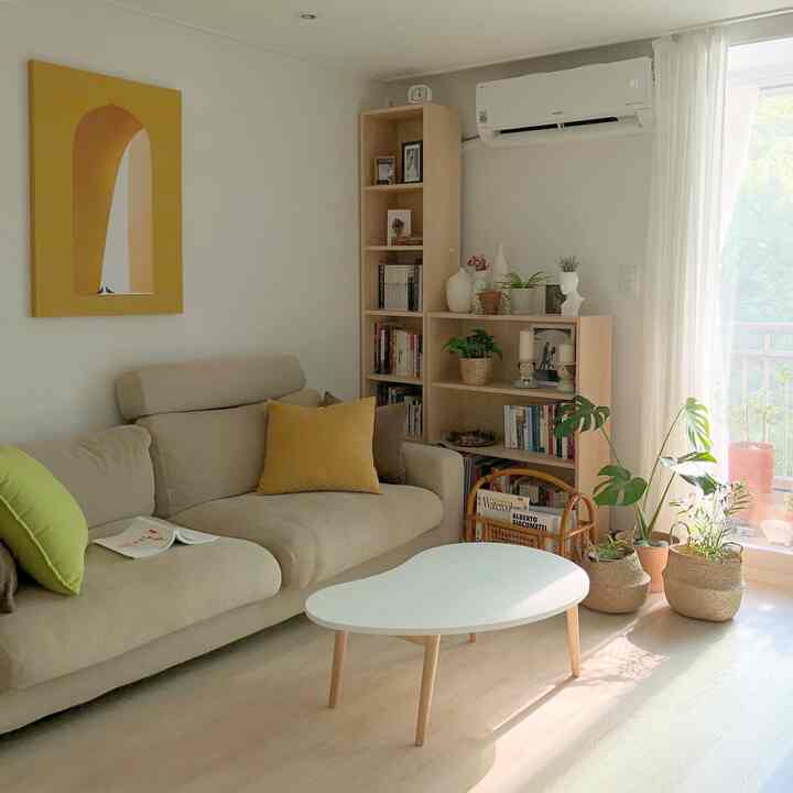 Bright living room with soft beige sofa and wood tones, accented by yellow cushions and a large yellow canvas in a natural style interior