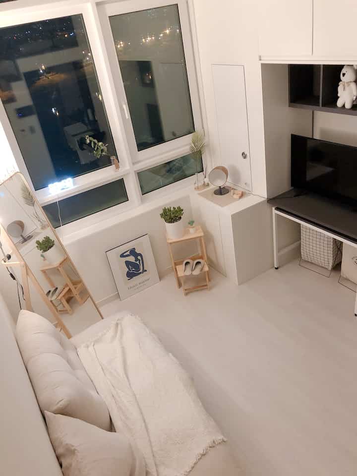 White and natural toned small living room featuring wood step stool, ivory sofa, and framed art creating a cozy space