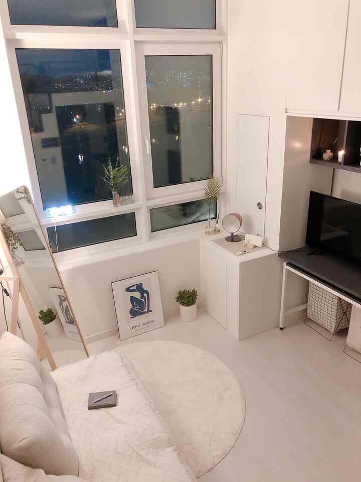 Cozy white-tone living room for single household, featuring round rug, full-length mirror, and sofa in a natural modern style