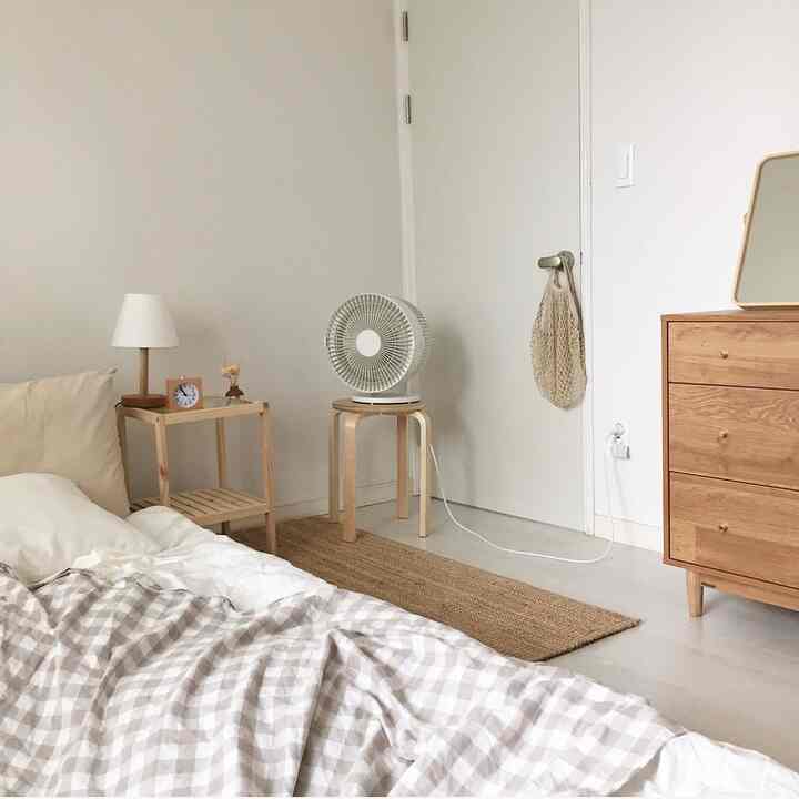 Beige and natural wood-tone bedroom featuring checked duvet cover and wooden nightstand creating a warm atmosphere
